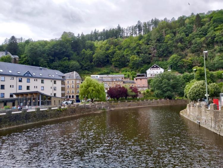 brede rivier met aan de zijkant gebouwen en bossen op de heuvelachtige achtergrond