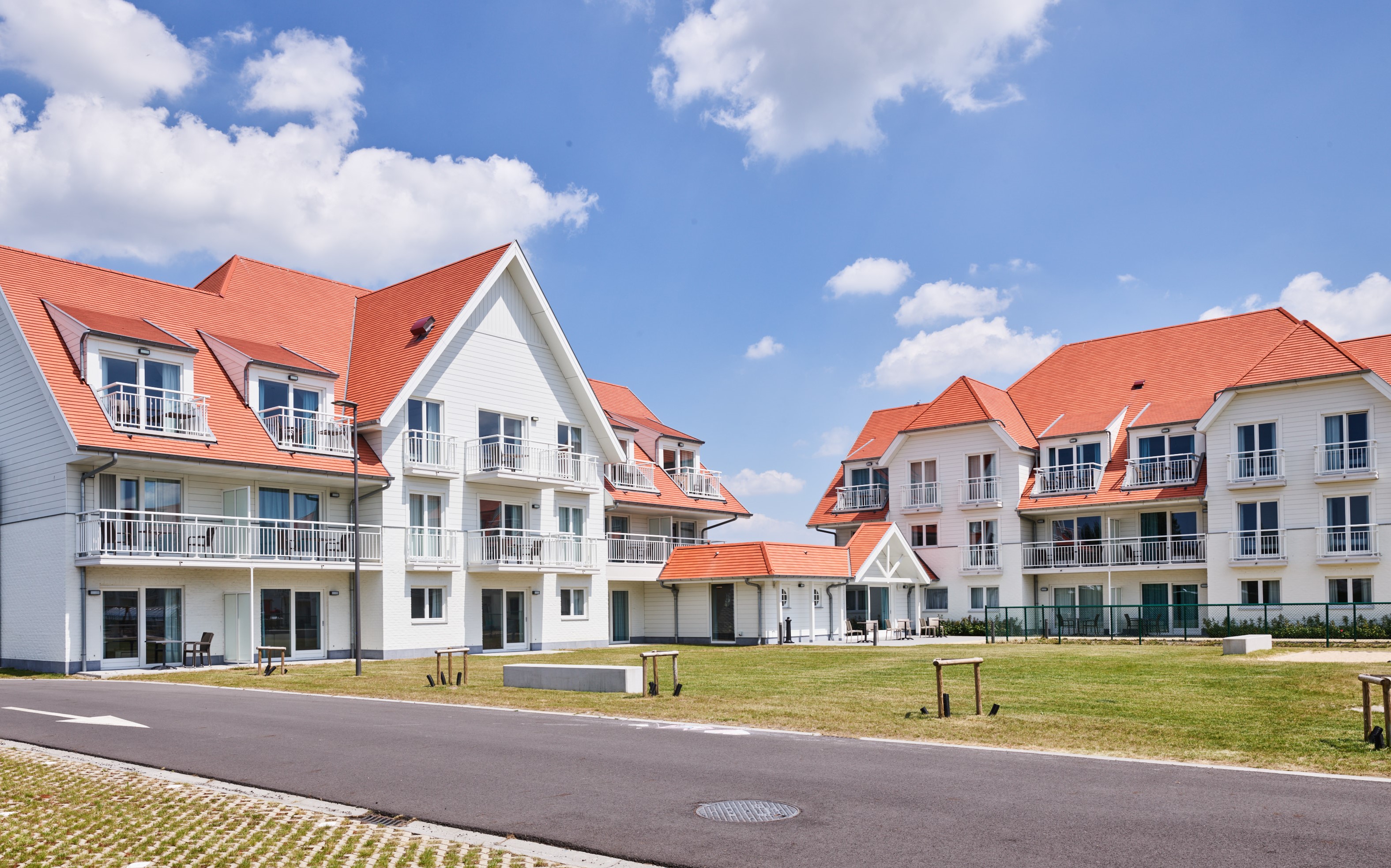 vakantiegebouwen met grasvlakte ervoor en blauwe hemel