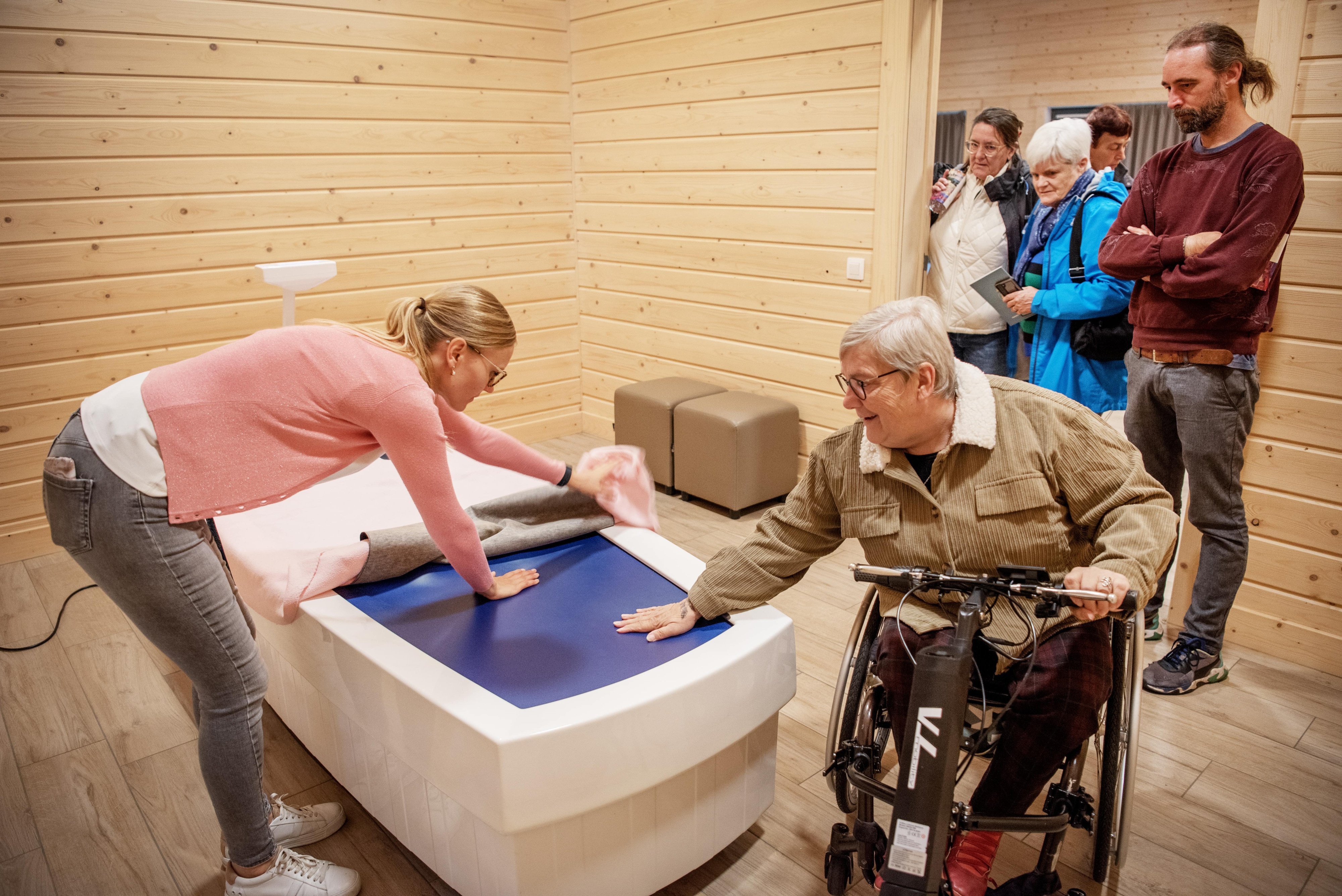 dame in rolstoel die speciale matras test en groepje mensen die staat te kijken