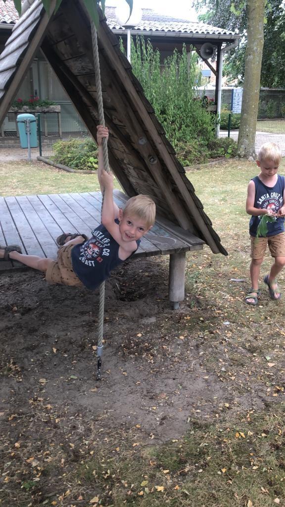 jongen die aan klimtouw hangt in een speeltuin