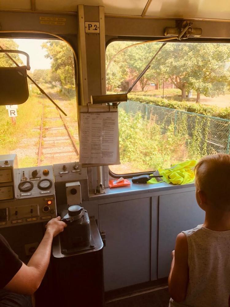 jongen die meekijkt vanuit cockpit van locomotief